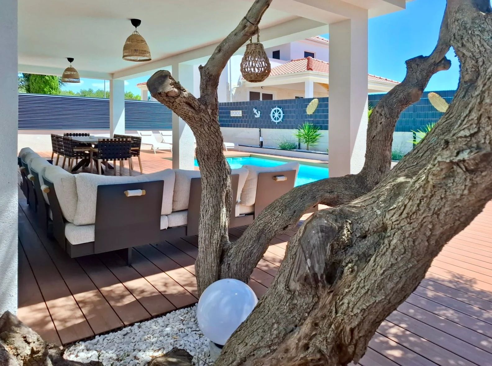 An outdoor lounge area with a pool, wooden deck, and lounge furniture.