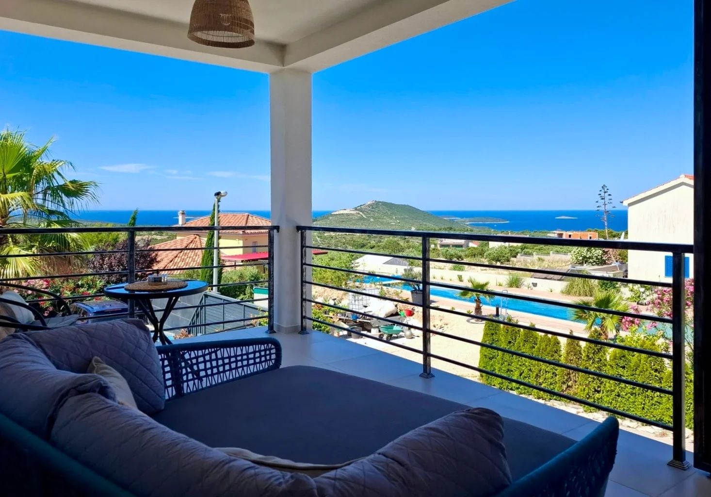 Un balcón con vistas a una piscina y al mar.