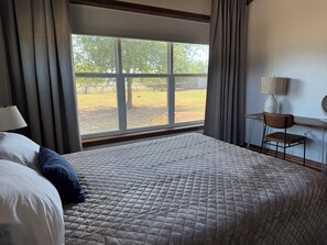 Ett hotellrum med en stor säng, ett skrivbord, en stol och ett fönster med utsikt över en innergård.