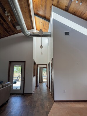 A spacious interior with a high ceiling, a central hallway, and a view through a door to an outdoor area.