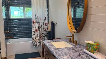 Une salle de bain avec une baignoire, deux lavabos, un miroir et une douche.
