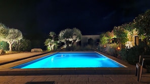 A rectangular swimming pool with a clear blue water surface, surrounded by a paved deck and illuminated by ambient lighting. - A beautiful bed-and-breakfast in the Ardèche, in a quiet setting surrounded by scrubland. (Joyeuse)