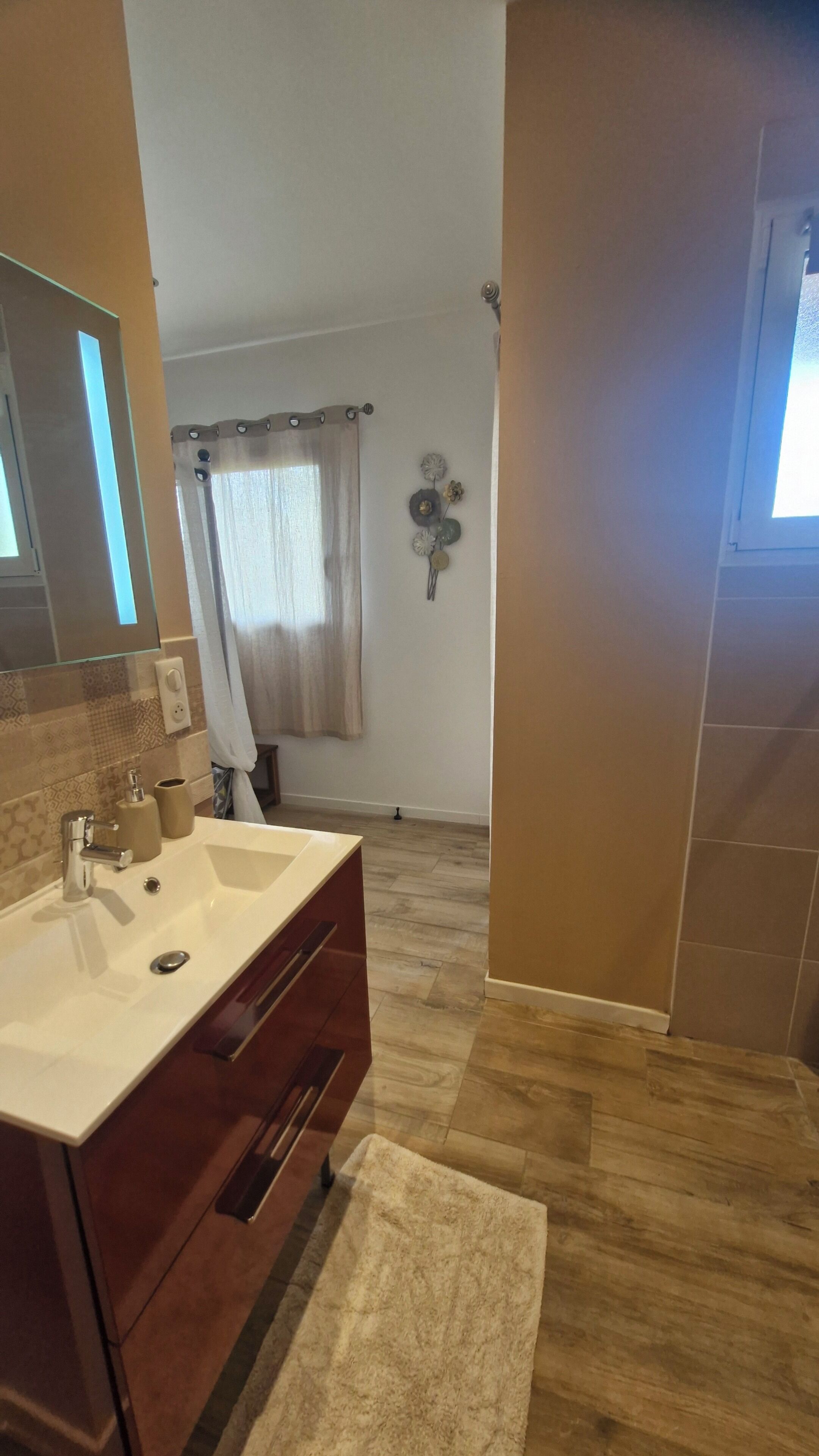Une salle de bain équipée d’un meuble-lavabo, d’un évier, d’un miroir et d’une zone douche.