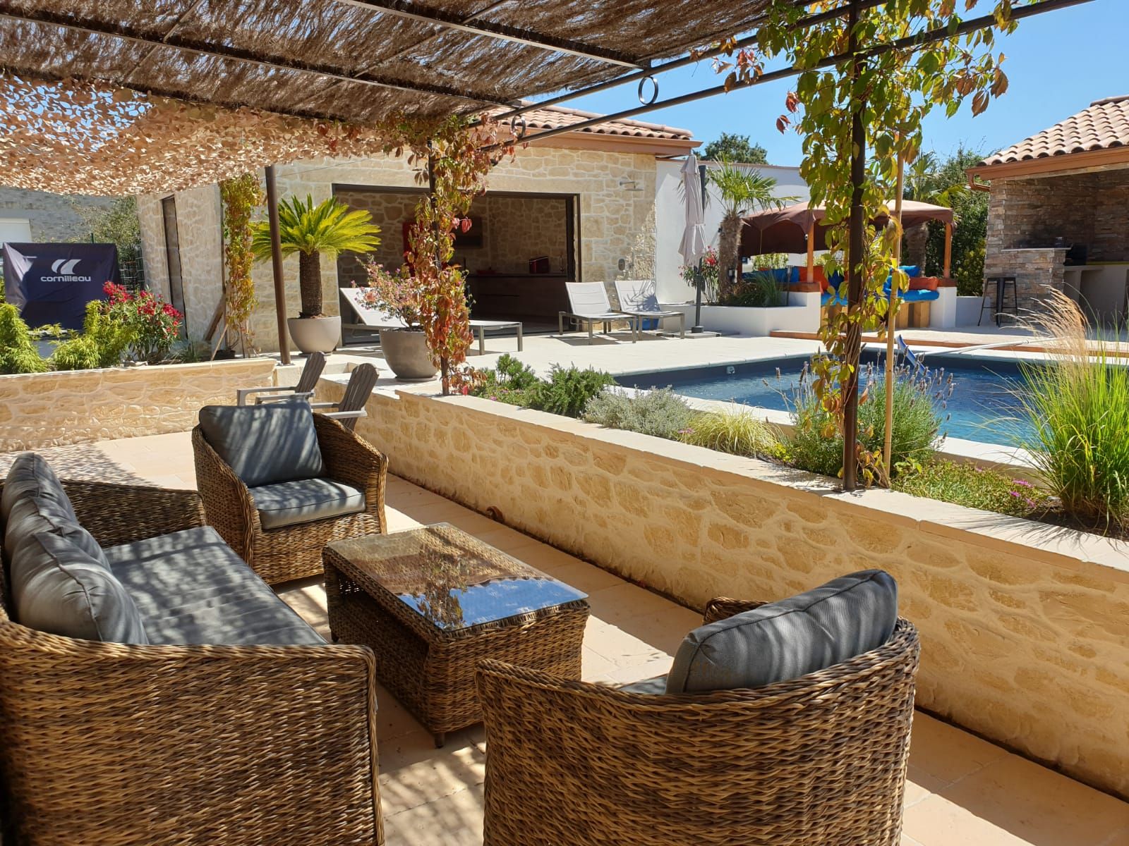 Un espace extérieur aménagé avec des meubles en osier, une piscine et un mur en pierre.