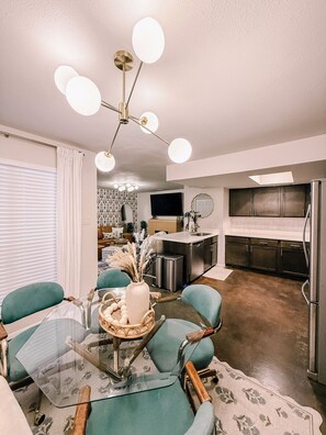 A modern living room with a glass coffee table, teal chairs, and a contemporary chandelier. - Boho-Chic Guesthouse near South Congress w/ 2 King Beds & Free Parking (Austin)