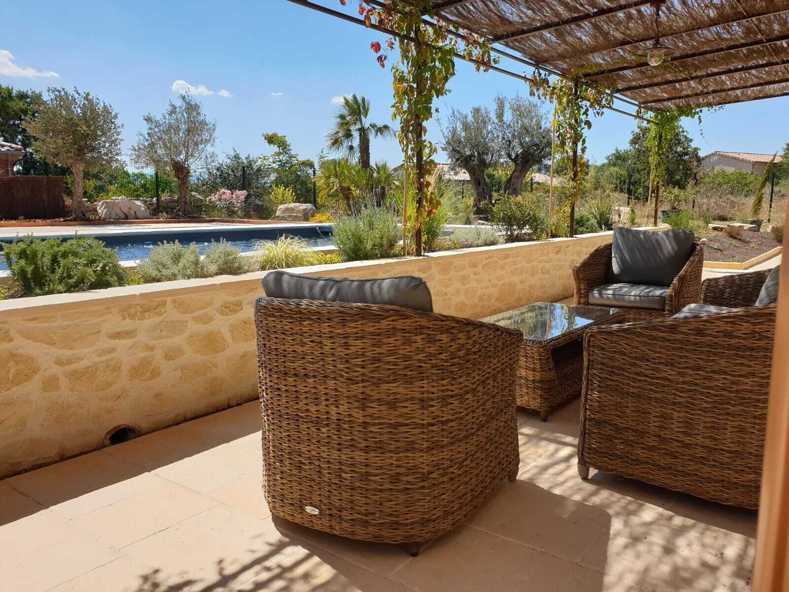 Un espace extérieur aménagé avec des meubles en osier et offrant une vue sur une piscine.