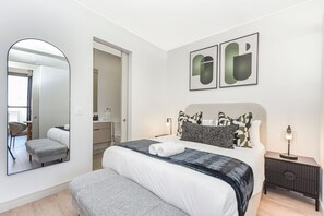 A modern hotel room with a large bed, a bedside table, a nightstand, a mirror, and two abstract paintings on the wall. - Contemporary Comfort with Natural Elegance (Johannesburg)
