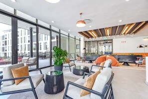 A modern lounge area with seating, a potted plant, and a view of the building's exterior. - Contemporary Comfort with Natural Elegance (Johannesburg)