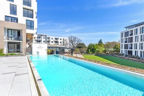 Un bâtiment moderne doté d’une piscine, d’un espace extérieur aménagé et d’une pelouse bien entretenue.