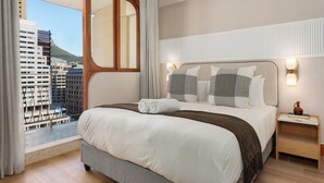 Ein Hotelzimmer mit einem großen Bett, Blick auf die Stadt und modernem Design.