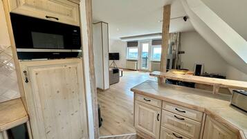 A modern kitchen with wooden cabinetry, a built-in microwave, and a large window providing natural light.