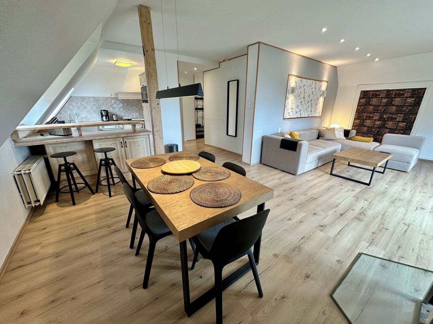 A modern living space with a dining area, kitchen, and seating area.