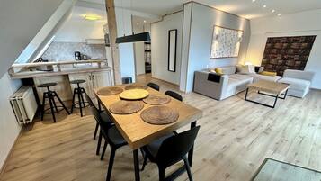 A modern living space with a dining area, kitchen, and seating area.