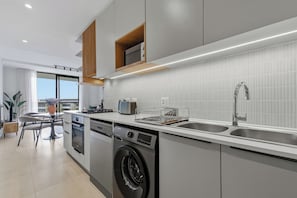A modern kitchen with built-in appliances, a dishwasher, and a double sink. - Luxe 2xBR Apartment | Ocean Views | Aircon (Umhlanga)