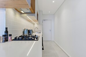 Een moderne keuken met een ingebouwde kookplaat, een koffieapparaat en diverse keukenapparaten.