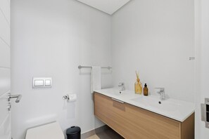 A modern bathroom with a white vanity, two sinks, a mirror, and a toilet. - Luxe 2xBR Apartment | Ocean Views | Aircon (Umhlanga)