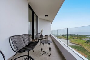 A balcony with two chairs and a small table, overlooking a river and greenery. - Luxe 2xBR Apartment | Ocean Views | Aircon (Umhlanga)