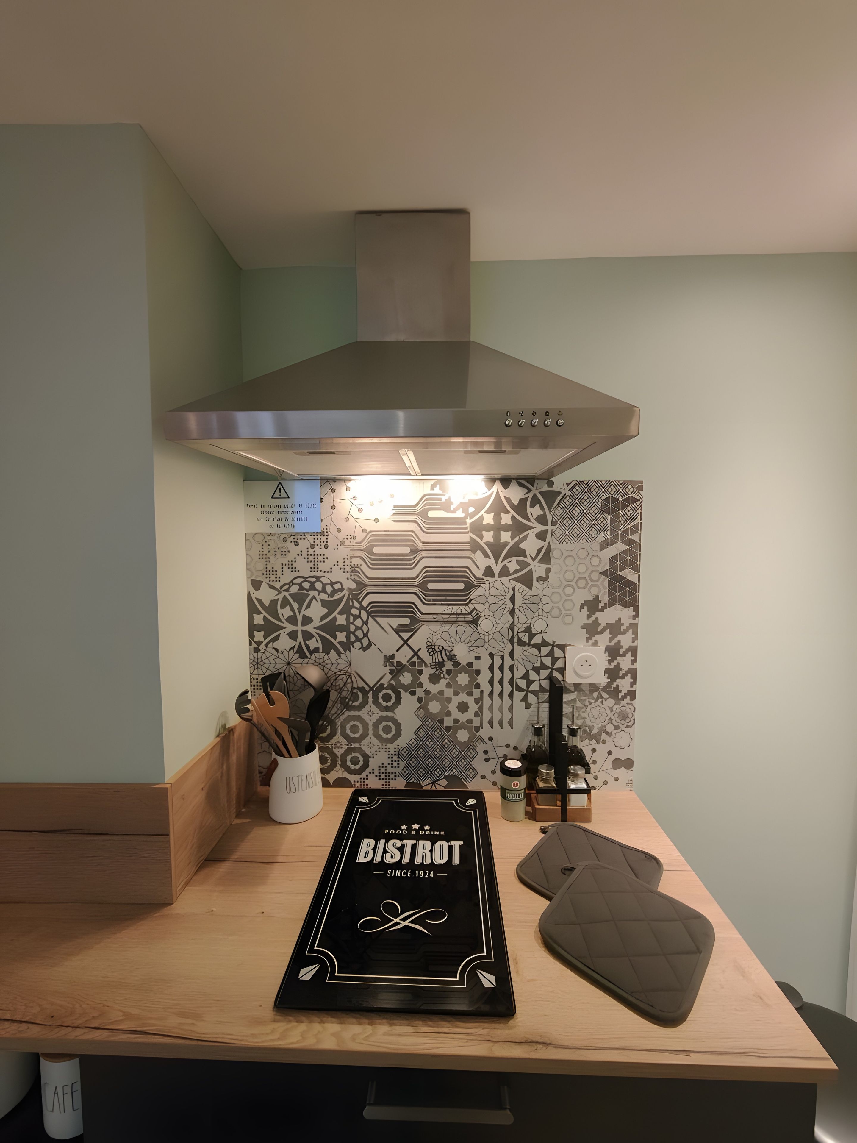 Une cuisine dotée d’une cuisinière moderne, d’un pare-feu orné de motifs géométriques et d’un plan de travail en bois.