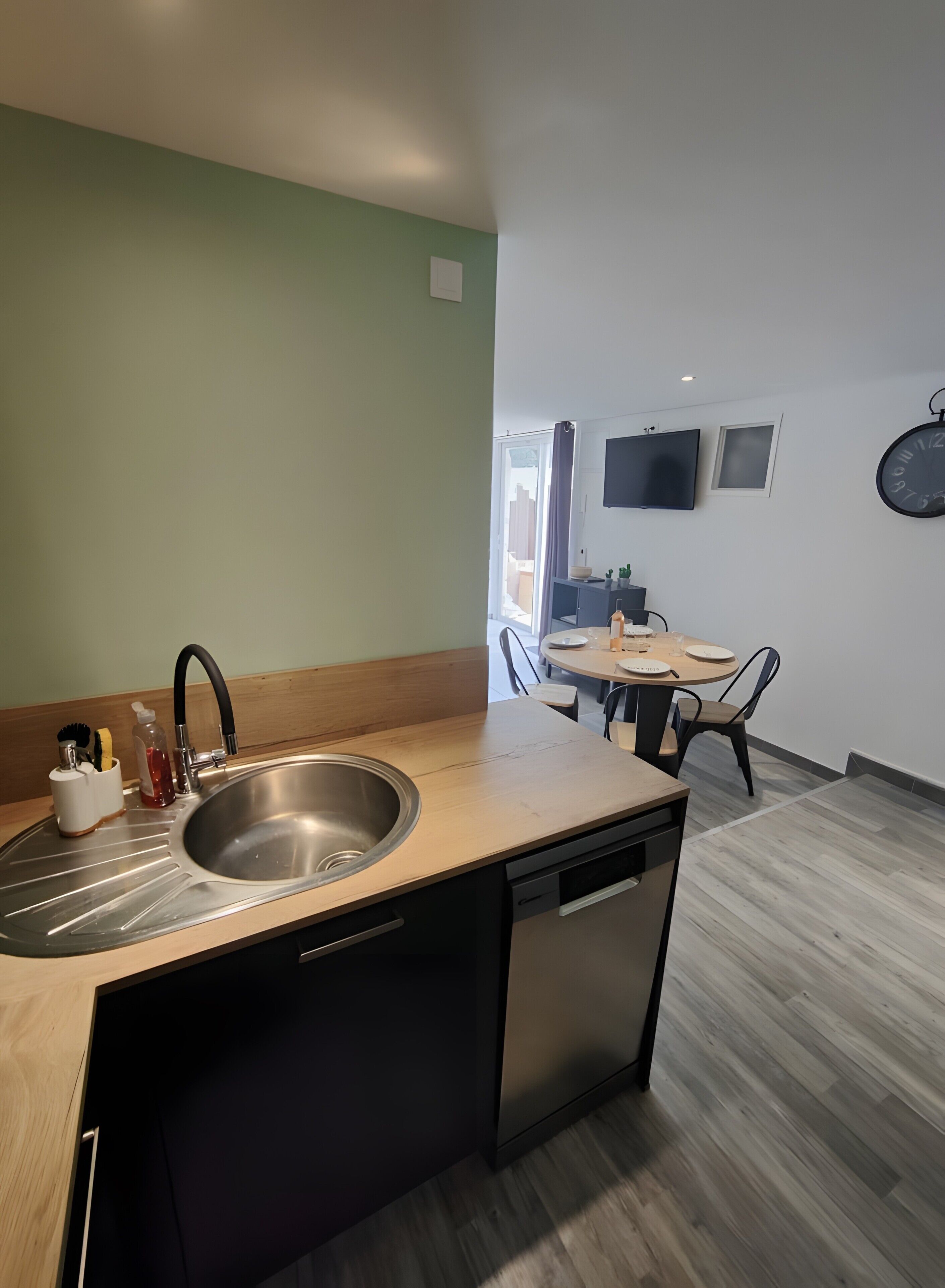 Une cuisine moderne équipée d’un lave-vaisselle, d’un évier et d’un coin repas avec une table et des chaises.