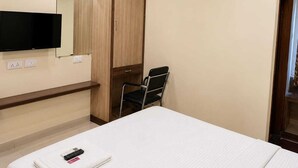 Quarto de hotel com cama, televisão na parede, guarda-roupa, cadeira e ar condicionado.