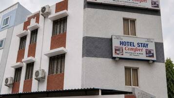 A hotel building with multiple signs advertising 'HOTEL STAY Comfort' and 'DELUXE A/C & NON A/C Rooms'.