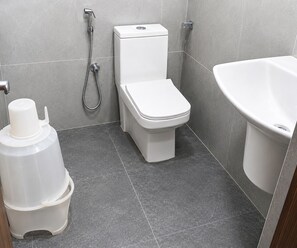 A bathroom with a toilet, a shower, and a sink. - Deluxe Room Hotel Stay Comfort (Hyderabad)