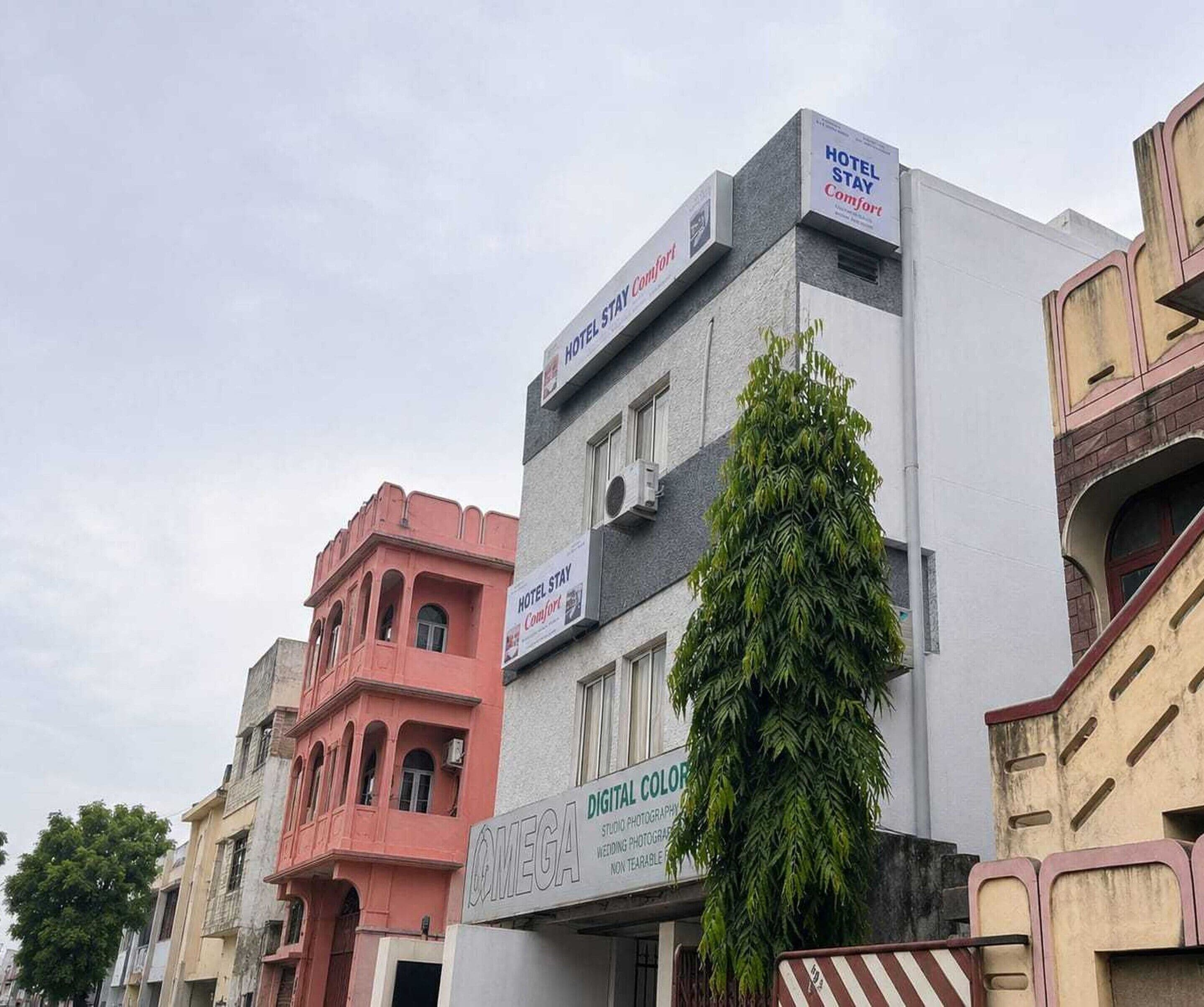 A multi-story building with signs for 'Hotel Stay Comfort' and 'OMEGA Digital Colour'.