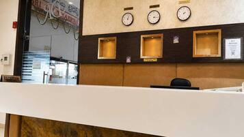 A hotel reception desk with clocks, a reception sign, and a sign indicating Wi-Fi reception.