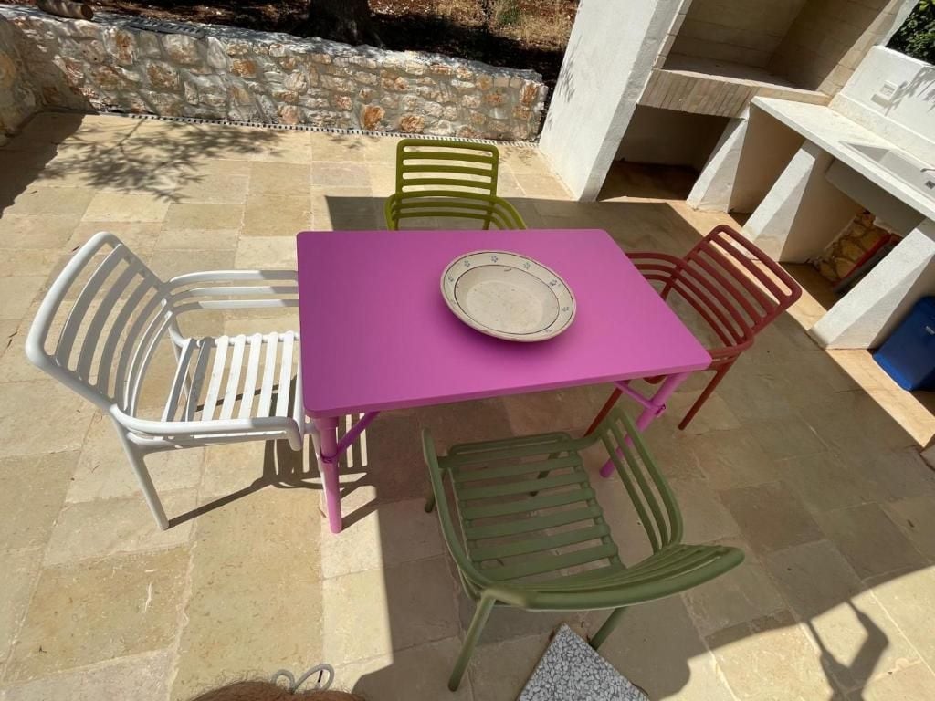 Une table carrée surmontée d’une assiette blanche, entourée de quatre chaises à ossature métallique.