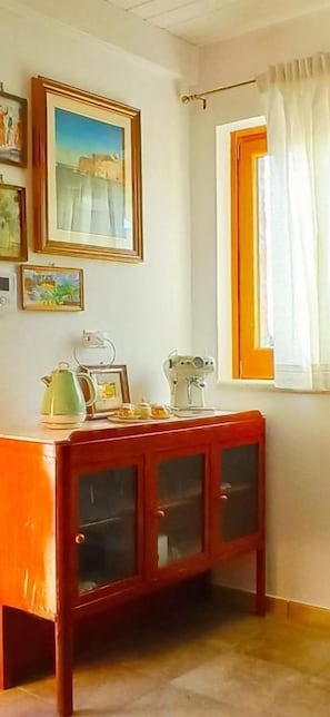 A room with a wooden cabinet, a sewing machine, and framed pictures on the wall.