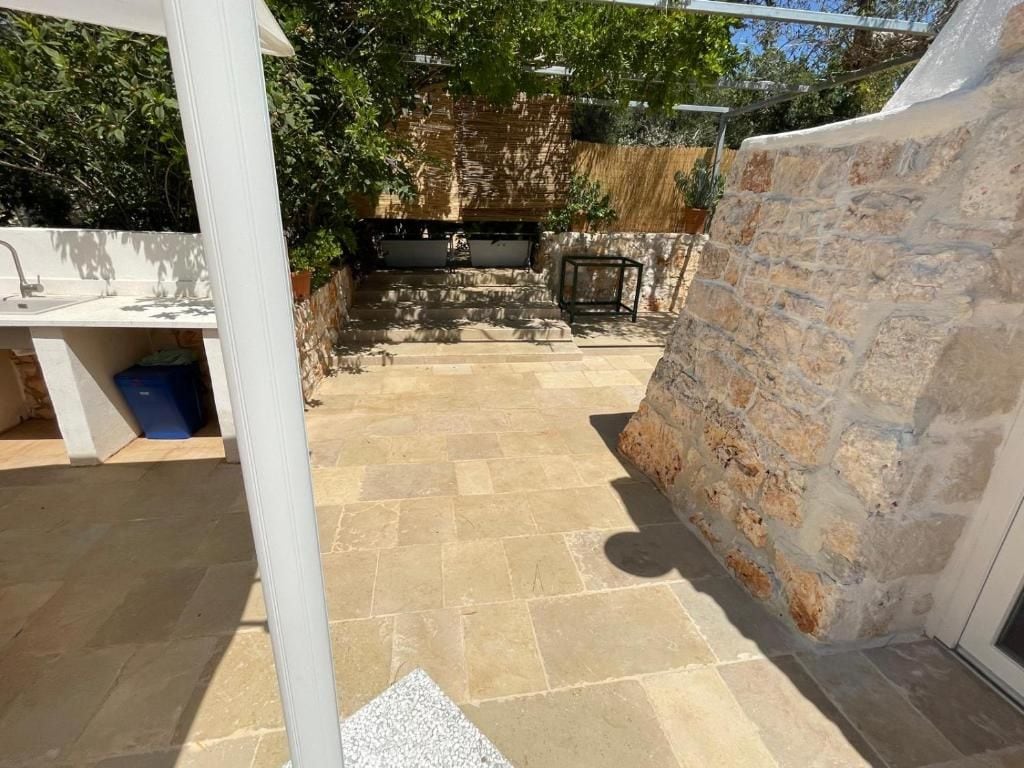 Un patio exterior con muro de piedra, pileta y parrilla.