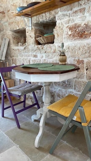 A rustic stone wall with a wooden table and two chairs.