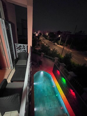 Ein Balkon mit Pool, Blick auf die Straße und Geländer.