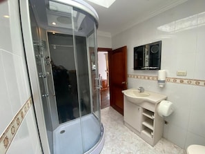 A bathroom with a glass-enclosed shower, a sink, and a toilet. - Hotel Coronel (Cuenca)