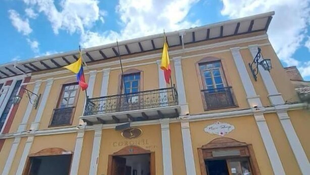 Um edifício com varanda, entrada de loja e um letreiro que diz 'Cortez'.