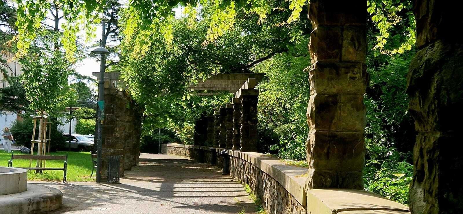 Un sendero de piedra que atraviesa un parque con árboles y una construcción de piedra.