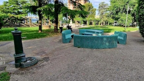 En park med en belagt sti, grønne bænke og en lysepost.