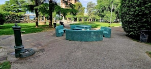 Ein Park mit befestigtem Weg, grünen Bänken und einem grünen Lampenpfosten.