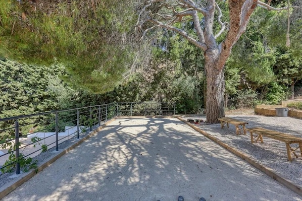 An outdoor area with a gravel surface, wooden benches, and a metal railing.