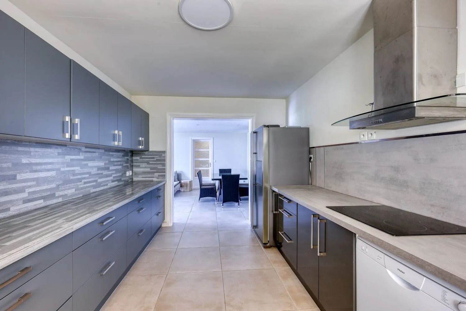 Una cucina moderna con mobili grigi, un frigorifero in acciaio inossidabile e un forno integrato.