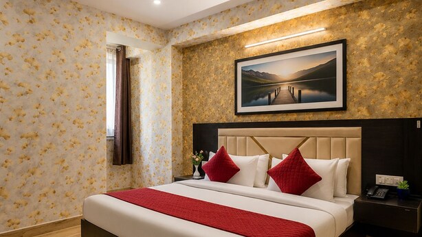 Ein Hotelzimmer mit einem Bett, einem Nachttisch, einem Deckenventilator, einem gerahmten Bild an der Wand und einem gemusterten Teppich.