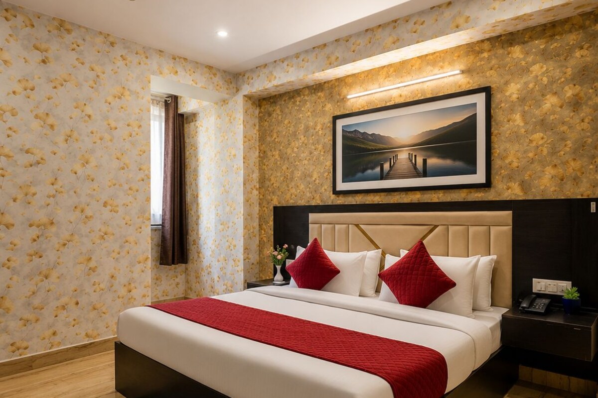 Ein Hotelzimmer mit einem Bett, einem Nachttisch, einem Deckenventilator, einem gerahmten Bild an der Wand und einem gemusterten Teppich.