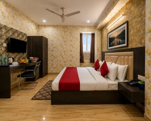 Ein Hotelzimmer mit einem Bett, einem Schreibtisch, einem Stuhl und einem Fernseher.