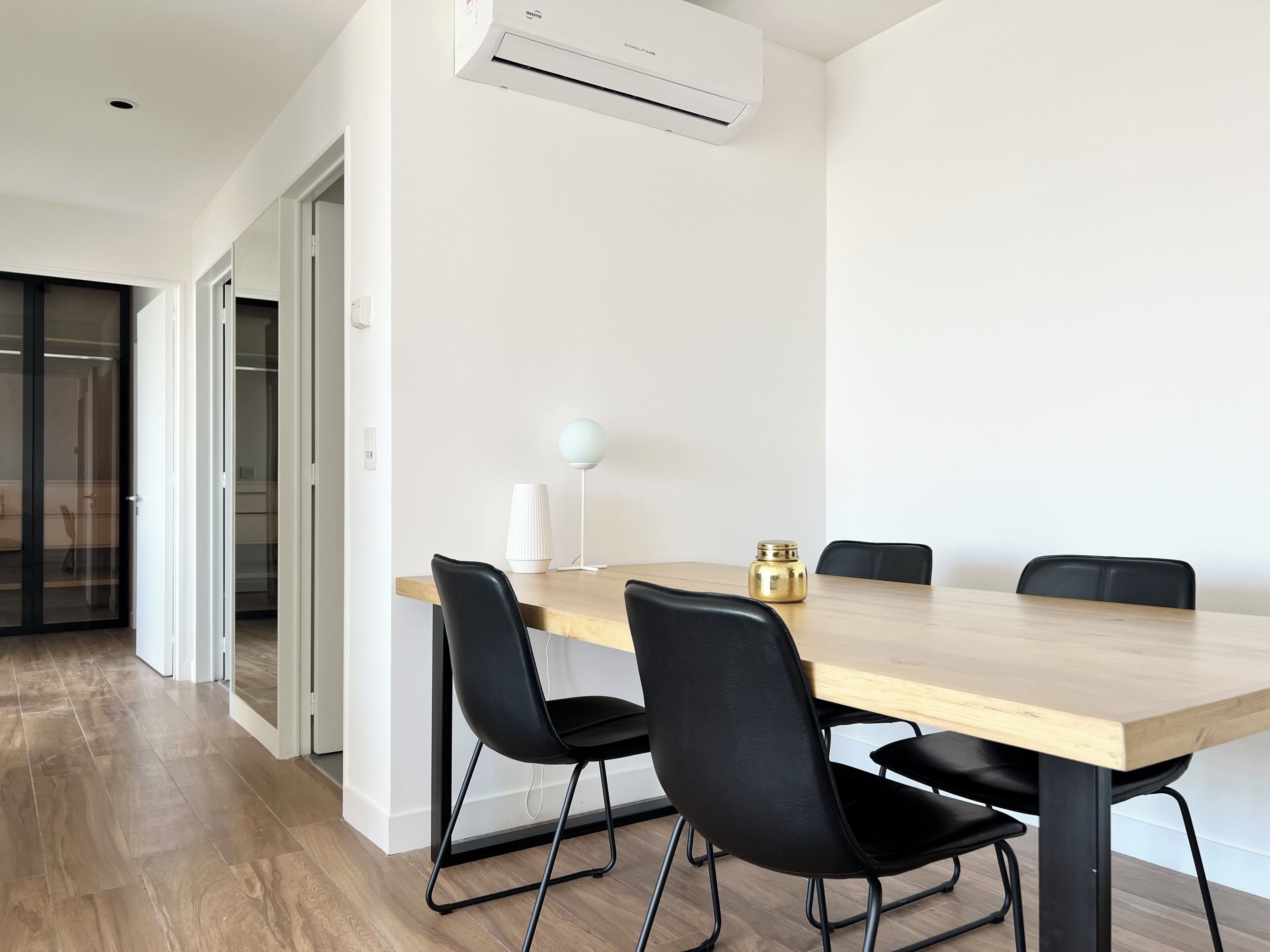 Un comedor moderno con una mesa de madera, sillas negras, una lámpara blanca y un adorno dorado.