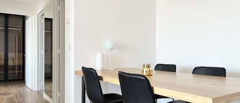 Un comedor moderno con una mesa de madera, sillas negras, una lámpara blanca y un adorno dorado.