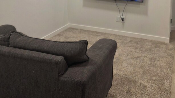 A living room with a flat-screen TV mounted on the wall, a gray couch, and a small shelf with a plant. - Cozy 2BR, 1Bath Suite in NW Calgary, Near Airport. (Calgary)
