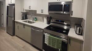 A modern kitchen with stainless steel appliances, white cabinetry, and a tiled backsplash. - Cozy 2BR, 1Bath Suite in NW Calgary, Near Airport. (Calgary)
