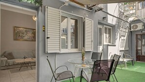 Et værelse med et glasbord og stole, en sofa og et billede på væggen.