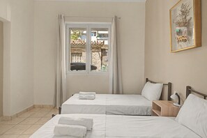A hotel room with two beds, a window with curtains, a bedside table with a lamp, and a framed picture on the wall. - Apartment 'Colonus' with Shared Terrace, Wi-Fi and Air Conditioning (Αθήνα)