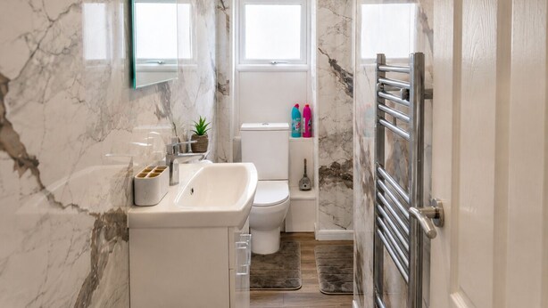 Une salle de bain avec un mur en marbre, un lavabo, des toilettes et un espace douche.